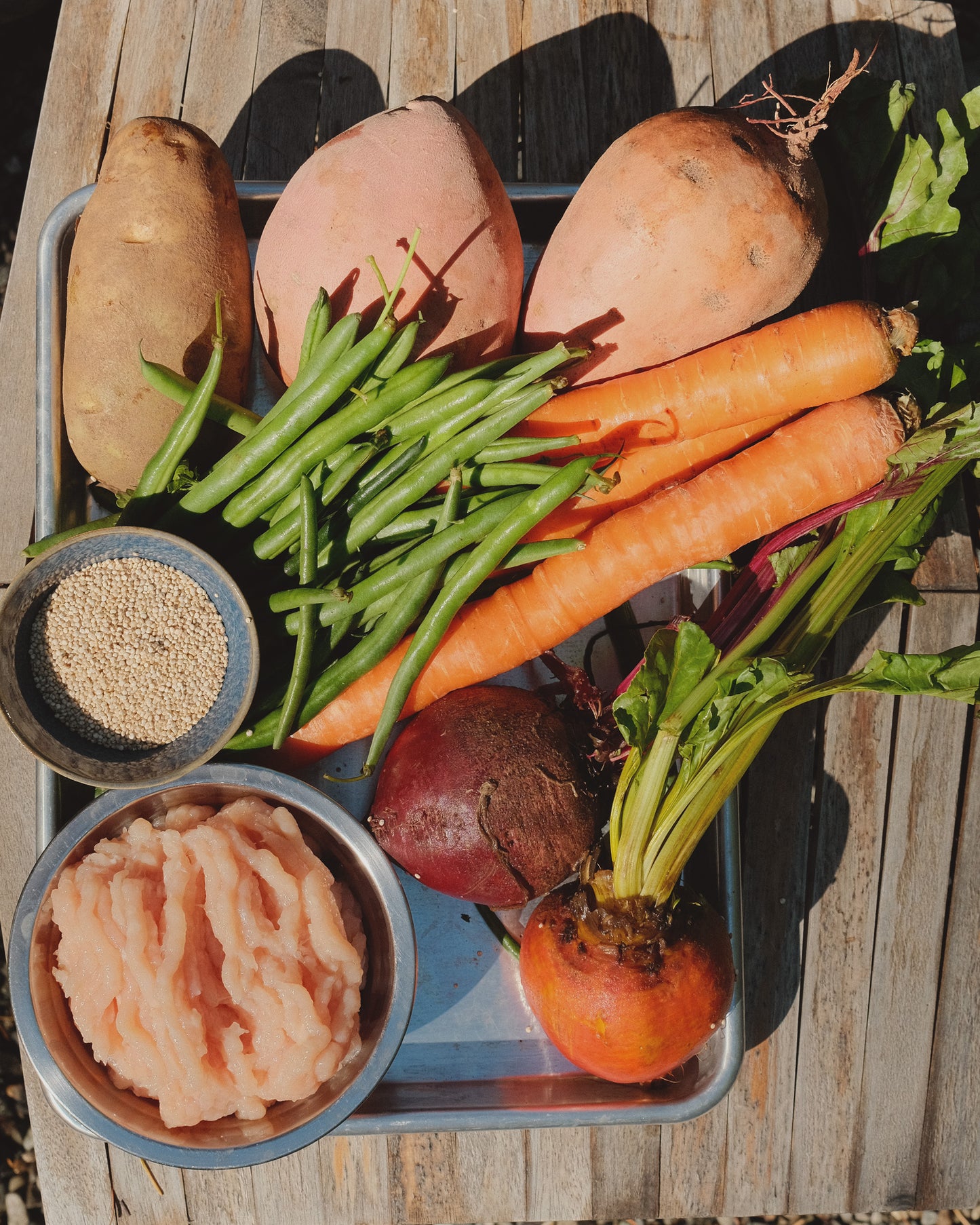 Assorted vegetables including carrots, green beans, sweet potatoes, and beets on a tray with a wooden background.