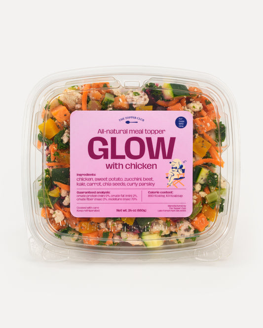 Packaged dog meal topper with visible ingredients and a pink label on a white background